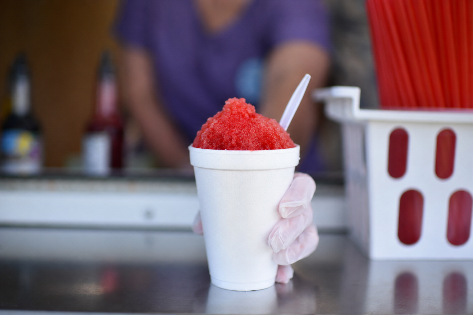 Close-up of a bright red snowcone being handed to a customer