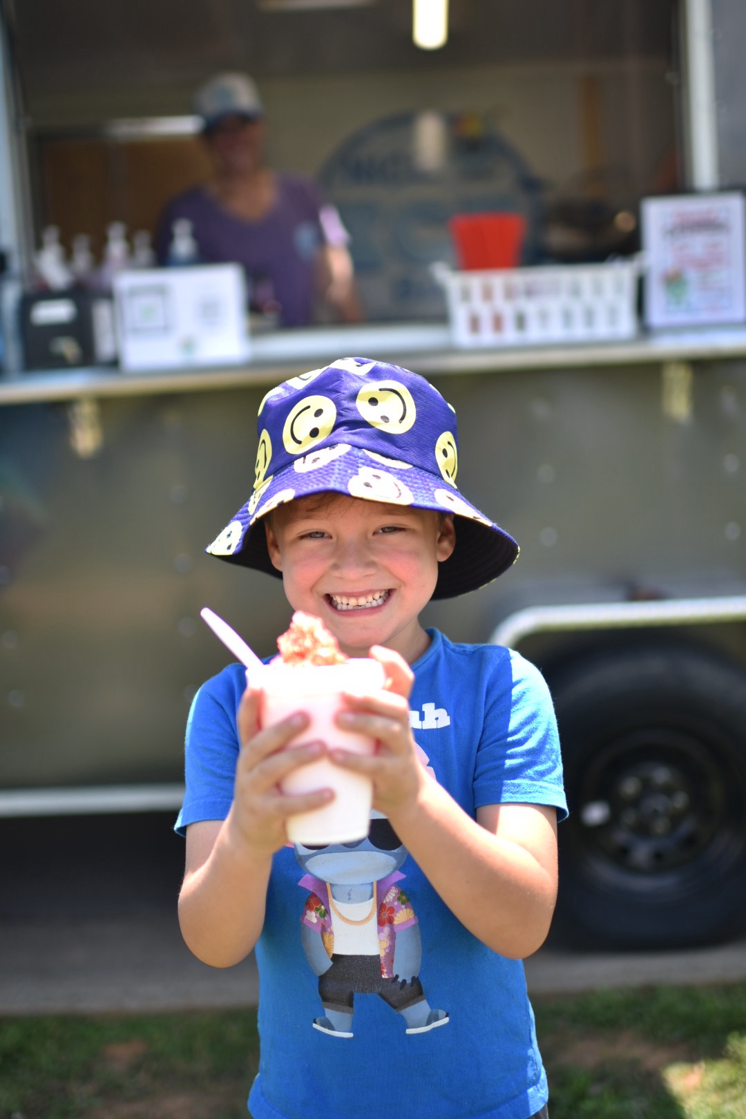 Smiling child holding up a snowcone in front of the Nice Ice Baby truck